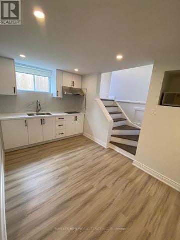 Markham (Bullock) apartment for rent - A kitchen with white cabinets and a staircase leading to the upper floor.