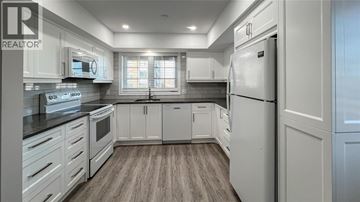 Point Edward condo for rent - A modern kitchen with white cabinets and a refrigerator.
