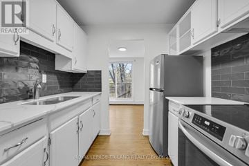 Strathroy-Caradoc (Nw) multi-family for rent - A modern kitchen with white cabinets and stainless steel appliances.