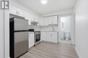 London South (South G) multi-family for rent - A kitchen with white cabinets and a stainless steel refrigerator.