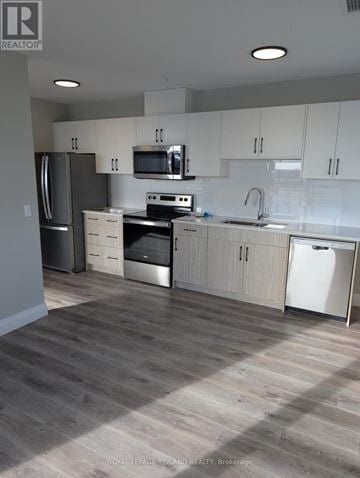 London North (North C) apartment for rent - A kitchen with white cabinets and a wooden floor.