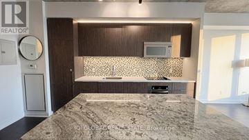 Toronto (Waterfront Communities) condo for rent - A bedroom with a large bed and a flat screen TV mounted above a cabinet.