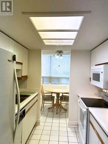 London East (East F) condo for rent - A kitchen with white appliances and a table with chairs.