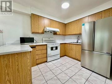 Toronto (Hillcrest Village) townhouse for rent - A kitchen with wooden cabinets and a white countertop.