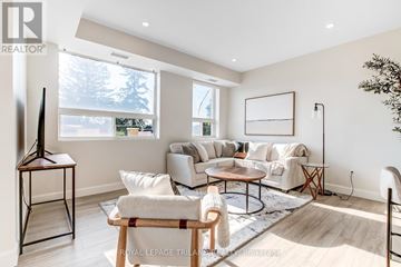 Central Elgin multi-family for rent - A living room with a white sofa set, a wooden coffee table, and a large window.