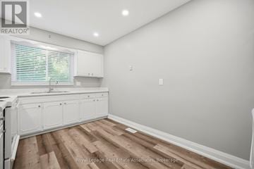 Brantford triplex for rent - A kitchen with white cabinets and a wooden floor.