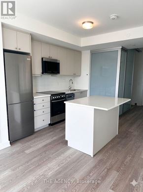Clarington (Bowmanville) condo for rent - A kitchen with a refrigerator, microwave, oven, and sink.