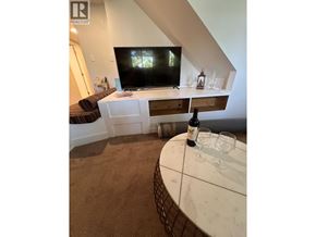 Vancouver apartment for rent - A living room with a television and a table with a bottle of wine on it.
