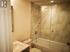 Toronto (Annex) condo for rent - A bathroom with marble tiles and a glass shower stall.