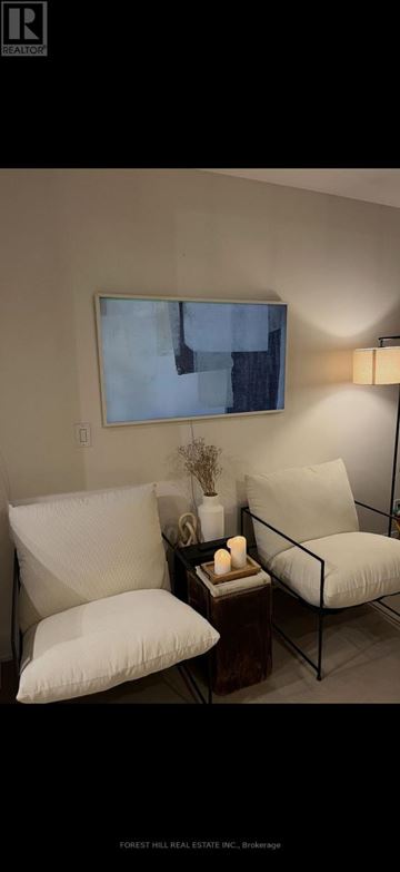 Toronto (Annex) condo for rent - A living room with a couch, a chair, and a table with a vase and candles on it.