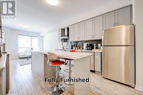 Oshawa (Samac) townhouse for rent - A fully furnished kitchen with a refrigerator, stove, and bar stools.