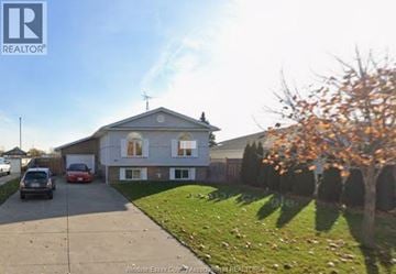 Amherstburg apartment for rent - A house with a driveway and a tree with orange leaves.