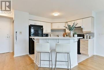 Toronto (Mimico) condo for rent - A kitchen with white cabinets and a black fridge.