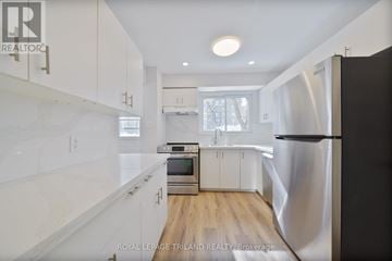 London South (South Q) townhouse for rent - A modern kitchen with white cabinets and a stainless steel refrigerator.