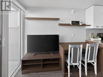 Waterloo condo for rent - A modern living room with a television and two chairs.