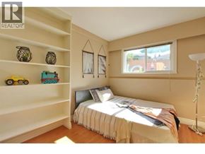 Burnaby apartment for rent - A bedroom with a bed, a window, and a shelf with toys on it.