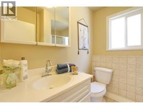 Burnaby apartment for rent - A bathroom with a toilet, sink, and mirror.