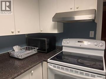 Vancouver apartment for rent - A kitchen with a white oven and a microwave on the counter.