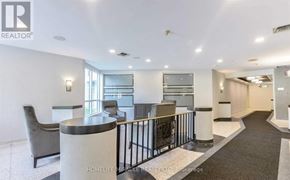 Brampton (Queen Street Corridor) condo for rent - A spacious living room with a black railing and a grey sofa.
