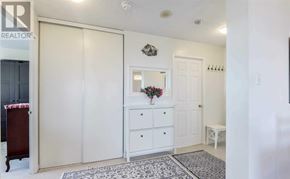 Brampton (Queen Street Corridor) condo for rent - A white room with a rug and a white dresser with a vase of flowers on top.