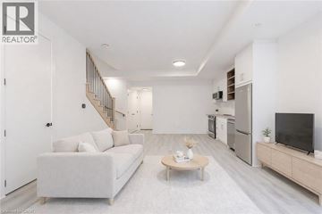St. Catharines townhouse for rent - A living room with a white couch, a wooden coffee table, and a television on a cabinet.