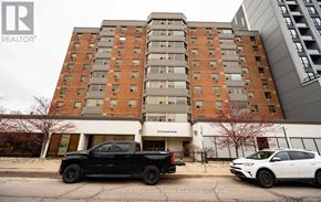 Guelph (Downtown) condo for rent - A black pickup truck is parked in front of a multi-story building.