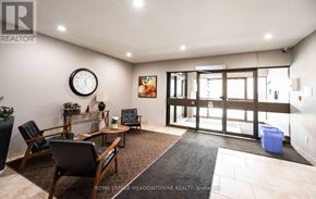 Guelph (Downtown) condo for rent - A living room with a couch, chairs, and a clock on the wall.