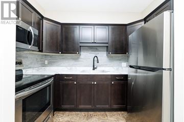 Fort Erie (Central) multi-family for rent - A kitchen with dark wood cabinets and stainless steel appliances.