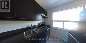 Toronto (Long Branch) apartment for rent - A kitchen with black cabinets and a stove top oven.
