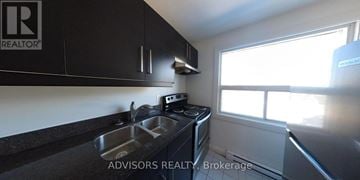 Toronto (Long Branch) apartment for rent - A kitchen with black cabinets and a stove top oven.