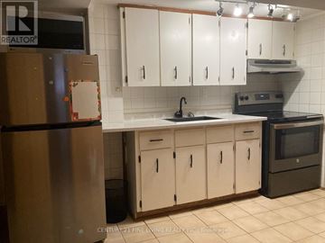 Toronto (Caledonia-Fairbank) apartment for rent - A kitchen with white cabinets and a black fridge.