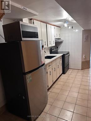 Toronto (Caledonia-Fairbank) apartment for rent - A kitchen with a black fridge and white cabinets.