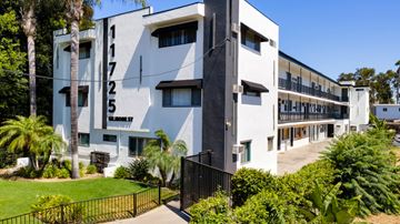 North Hollywood apartment for rent - A white building with black numbers on the side and a black fence in front.