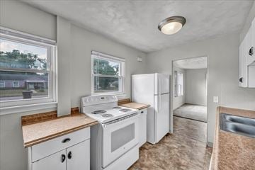 Lansing apartment for rent - A kitchen with white appliances and a window overlooking a house.