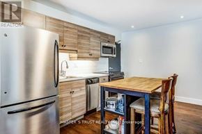 Aurora (Aurora Heights) apartment for rent - A kitchen with a stainless steel refrigerator, wooden cabinets, and a wooden table with chairs.