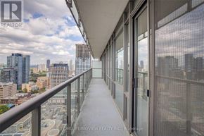 Toronto (Bay Street Corridor) condo for rent - A balcony with glass doors overlooking a cityscape.