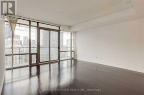 Toronto (Bay Street Corridor) condo for rent - A spacious room with a large window overlooking a cityscape.