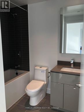 Toronto (Bay Street Corridor) condo for rent - A white toilet in a bathroom with a sink and mirror.
