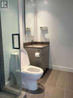 Toronto (Bay Street Corridor) condo for rent - A white toilet in a bathroom with a glass shower door.