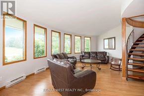 Adjala-Tosorontio apartment for rent - A living room with a brown leather couch and a spiral staircase.