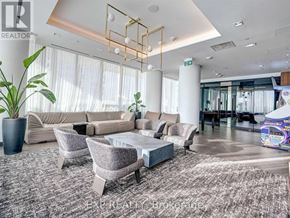 Vaughan (Vaughan Corporate Centre) condo for rent - A living room with a grey rug, a grey sofa, a grey armchair, a grey coffee table, a potted plant, and a glass door.