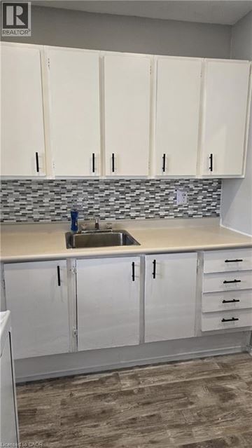 Hamilton condo for rent - A kitchen with white cabinets and a sink.