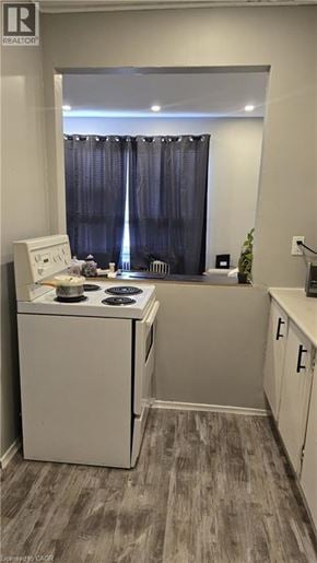 Hamilton condo for rent - A small kitchen with a stove and a window with curtains.