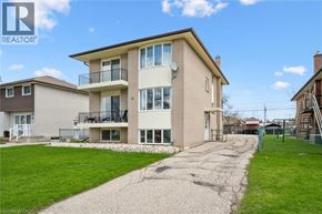 Kitchener apartment for rent - A two-story apartment building with a balcony and a driveway in front.