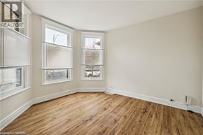 Hamilton apartment for rent - A room with wooden floors and two windows.