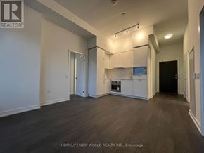 Toronto (Newtonbrook East) condo for rent - A spacious kitchen with white cabinets and a black refrigerator.