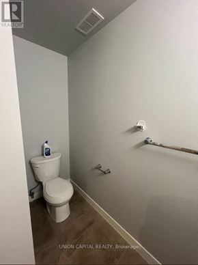 Waterloo condo for rent - A white toilet sits in a small bathroom with a white wall and a white towel rack.