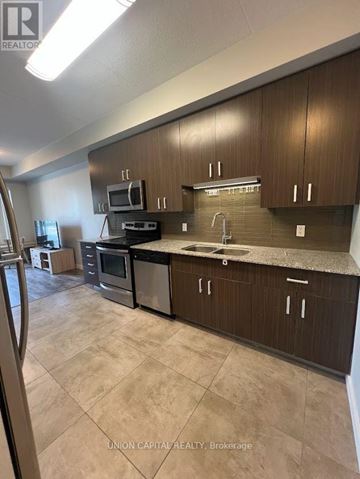 Waterloo condo for rent - A kitchen with brown cabinets and a black counter top.