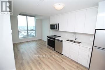 Kitchener condo for rent - A kitchen with white cabinets and a black dishwasher.