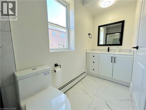 Stoney Creek apartment for rent - A white bathroom with a toilet, sink, and mirror.